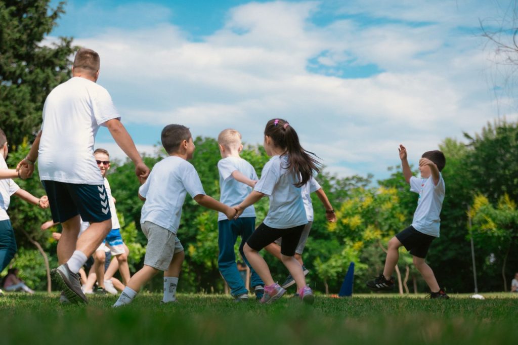 Group of children having fun and playing games together in a sunny park.